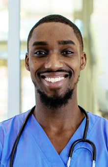 Male nurse smiles at camera with stethoscope around his neck.