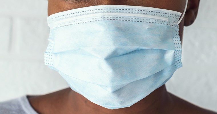 Close-up of a woman wearing a blue, disposable medical mask.