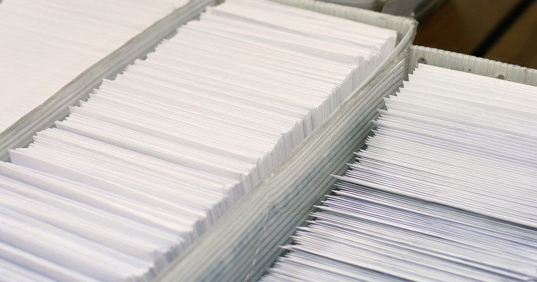 White envelopes located inside a mail sorting bin.