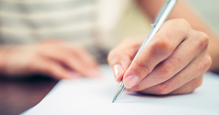 hand holding pen writing on paper